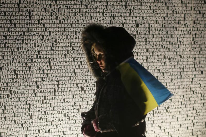 A girl stands at a monument with inscriptions of locations that suffered in the Holodomor famine, in Kiev, November 2014.