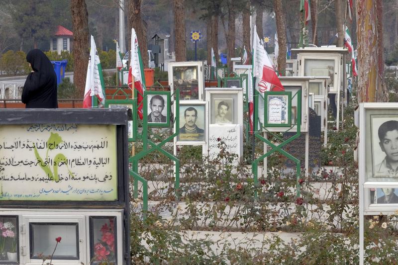 A woman walks amongst the graves of people killed during the 1979 Islamic Revolution in Behesht Zahra cemetery, south of Tehran, February 2016.